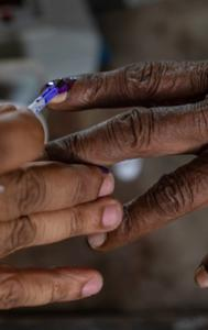 An official puts indelible ink mark on the index finger of a voter.