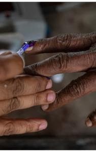 An official puts indelible ink mark on the index finger of a voter.